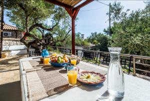 a table with a bowl of fruit and a bottle of orange juice at Villa Aeolus Stylish Villa with Pool Masterbedroom with seperate Mezzanine in Koríthion +5 photos