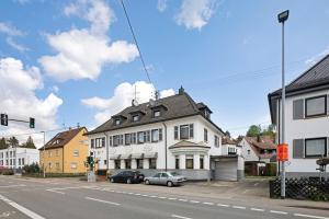 a street with cars parked in front of a white building at Hotel Garni Siedlerstube 2 in Nürtingen