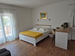 a bedroom with a bed and a table with a desk at Apartments Ivanovski in Rab