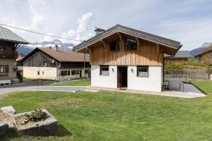 a wooden house with a green yard in front of it at Chalet Individuel - Saflalou in Combloux