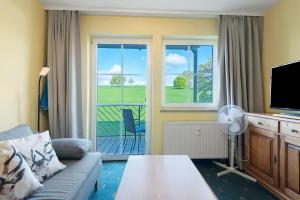 a living room with a couch and a tv and a balcony at Apartment mit Gartenblick K1 106 in Spalt