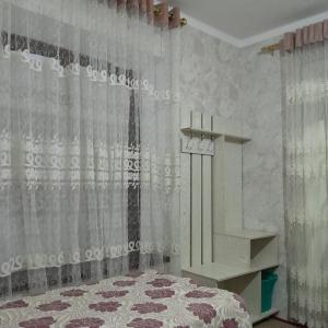 a bedroom with a bed and a shelf and curtains at Le Fortin in Samarkand