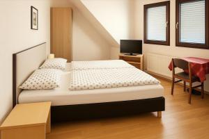 a bedroom with two beds and a desk and a television at Gasthaus Bidinger in Schoden