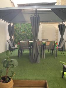 a patio with a table and chairs under an umbrella at Jul'Home pour 4 personnes , Terrasse avec Jacuzzi en centre ville Dax in Dax