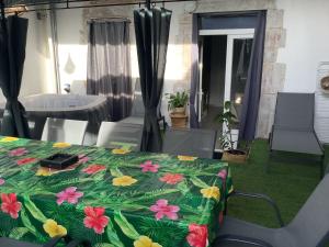 a bed with a green blanket with flowers on it at Jul'Home pour 4 personnes , Terrasse avec Jacuzzi en centre ville Dax in Dax
