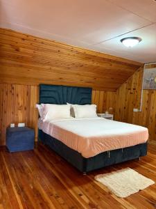 a bed in a room with wooden walls and wood floors at Kendi Stays - Rustic Penthouse Attic in Eldoret