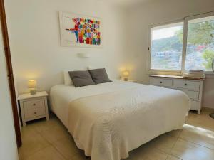 a bedroom with a white bed and a window at Stunning Intimate views. Terrace Rooftop. Wifi in Tamariu