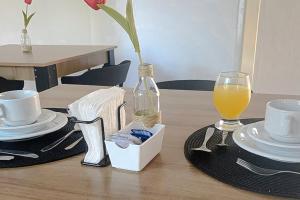 a table with plates and a glass of orange juice at VELINN Pousada Entre Praias Itaguá in Ubatuba +7 photos