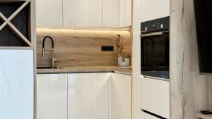 a kitchen with white cabinets and a sink and a microwave at Moonlight Luxury Apartment with Private Pool and Parking in Kaštela