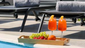 a tray of fruit with two drinks on a table at Moonlight Luxury Apartment with Private Pool and Parking in Kaštela