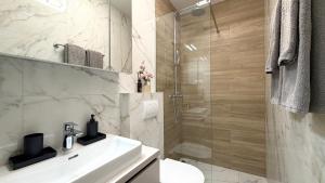 a bathroom with a white sink and a shower at Moonlight Luxury Apartment with Private Pool and Parking in Kaštela