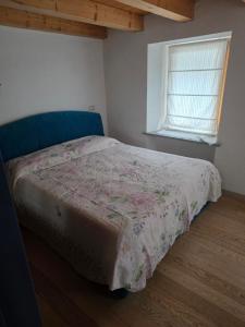 a bedroom with a bed with a floral bedspread and a window at la casa del marmottaio in Crépin