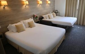 two beds in a hotel room with white sheets at Hotel Les Terrasses in Annecy