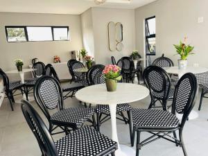 a dining room with tables and chairs and flowers at Overflow Accommodation Lodge in Louis Trichardt