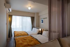 a hotel room with two beds and a window at The Apartment Hotel Shibuya 3 in Tokyo
