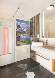 un baño con lavabo y una pintura en la pared en Hotel Zauchensee Zentral, en Zauchensee