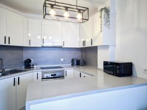 a kitchen with white cabinets and a black microwave at ELKO Apartman in Mogán