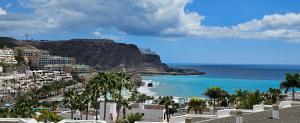 a view of a beach with palm trees and the ocean at ELKO Apartman in Mogán