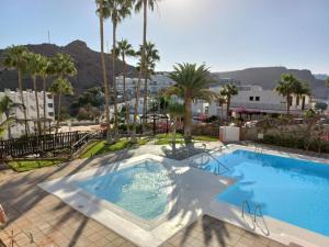a large swimming pool with palm trees and a building at ELKO Apartman in Mogán
