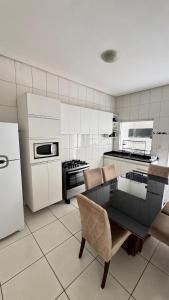 a kitchen with white appliances and a table and chairs at Casa jatobá in Petrolina