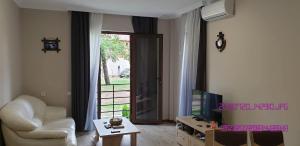 a living room with a white chair and a television at SHEKVETILI s in Kokotauri +5 photos