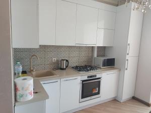 a kitchen with white cabinets and a stove top oven at Airport Transit Studio Ночь перед вылетом in Chişinău +1 photo