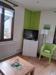 a living room with a tv and a chair and a table at le gite d'Eliane in Masevaux +6 photos