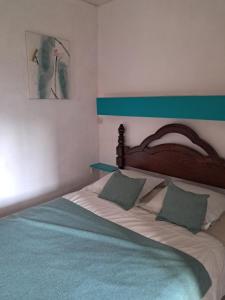 a large bed with a wooden headboard and two pillows at le gite d'Eliane in Masevaux