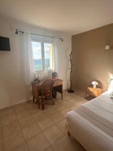a bedroom with a desk and a bed and a window at la maison CM in Nessa