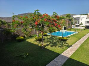 a garden with a tree with red flowers next to a swimming pool at La Casa Blanca VIP in Tlayecac