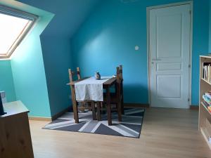 a dining room with a table and chairs and a blue wall at Oasis de Bonheur à Amaryllis in La Guierche