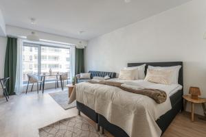 a bedroom with a large bed and a living room at Luminary - Tampere City Center Apartments by Come in! in Tampere