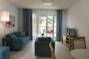 a living room with a blue couch and a tv at DOMITYS - Le Ruban d'Azur in Sète +8 photos