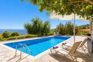 a swimming pool with chairs and an umbrella at Villa Panorama Tria in Drousha