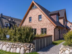 a brick house with a stone retaining wall at Dorfhüs 1 in Tinnum
