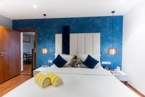 a bedroom with a large white bed with blue walls at DARZA LUXURY RESORTs in Coimbatore +20 photos