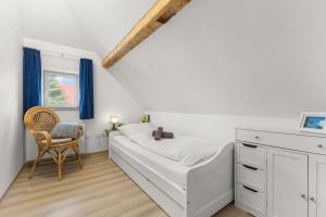 a white bedroom with a bed and a chair at Up Böhn in Krummhörn