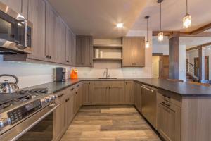 a kitchen with wooden cabinets and stainless steel appliances at Mountain Lake Condo - Unit 102B in Big Sky