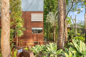 a house surrounded by trees with a bench in front at The Bamboo Base at Buderim in Buderim