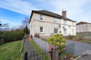 a white house with a fence in front of it at Goldie Apartment 2BR flat in Dalry
