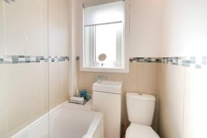 a bathroom with a toilet and a window and a tub at Goldie Apartment 2BR flat in Dalry +22 photos