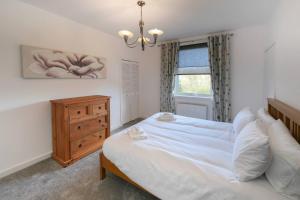 a bedroom with a bed and a dresser and a window at Goldie Apartment 2BR flat in Dalry