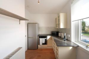 a kitchen with a stainless steel refrigerator and a window at Goldie Apartment 2BR flat in Dalry
