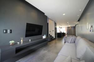 a living room with a white couch and a flat screen tv at Sobrado com Jacuzzi Aquecida 10 minutos Centro in Foz do Iguaçu