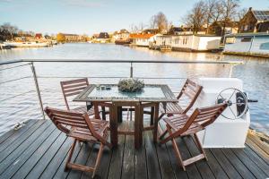 a table and chairs on a boat on the water at Rode Houseboat Zwartsluis in Zwartsluis