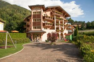 a building in the mountains with a brick driveway at Family Hotel Adriana in Ledro