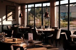 a restaurant with tables and chairs and windows at Auberge de la Hardouinais-Arduen in Saint-Launeuc