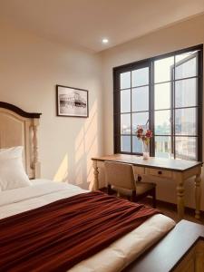 a bedroom with a bed and a desk and a window at Khách sạn Solea VIỆT TRÌ in Việt Trì