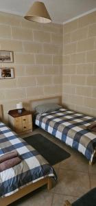 two beds in a room with a wall at Quiet, spacious 3 bedroom 2 bathroom apartment in Għajnsielem