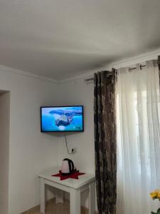 a room with a tv on a wall with a table at Dejani Guest House in Pogradec